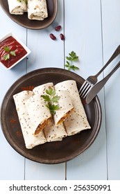 burritos wraps with meat beans and vegetables on blue wood board