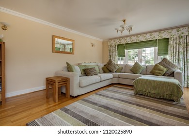 Burrough Green, Suffolk - July 12 2018: Modern Luxury Living Room With Heavily Patterned Rug And Corner Settee Sofa With Matching Cushions In Green