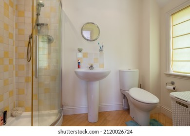 Burrough Green, Suffolk - July 12 2018: Shower Room With Corner Shower Cubicle Decorated In Lemon And White Tiles Plus Wc And Pedestal Sink