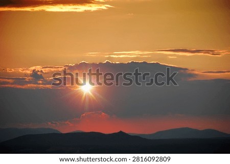 A burst of sunlight at sunset with rays streaming through the clouds. Mountains in the background, backlit. Apparition Hill in Medjugorje, Bosnia and Herzegovina.