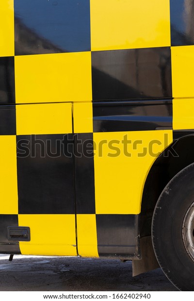 The bus body is covered in\
a checkerboard pattern. Yellow and black cell. Public transport\
design.
