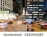 Bus and cars, captured with blurred motion, rush through a major interesection in the Central business and shopping district in Hong Kong at night