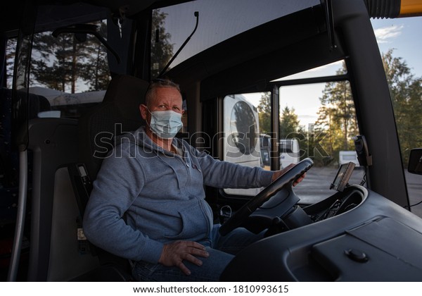 Bus driver in\
medical mask, leads the bus\
Safe driving during a pandemic,\
protection against\
coronavirus