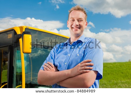 Bus driver is standing in front of his bus under al blue sky