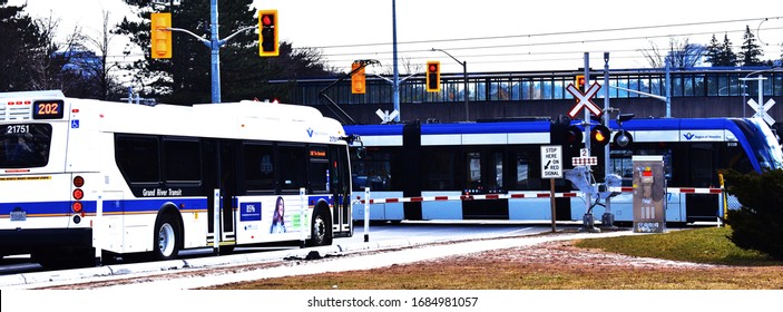 Bus From Grand River Transit Waiting On Railway Traffic Light During Light Rail Train Is Passing Near University Of Waterloo In Waterloo Region, Ontario, Canada March 25, 2020. 