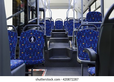 Bus Inside, City Transportation White Interior With Blue Seats In Row, Retirement Places, Open Doors, Handles For Standing Passengers, Bright Lights And Air Conditioner 