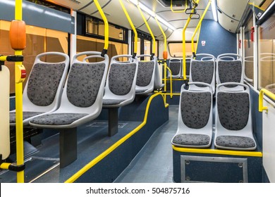 The bus inside. Grey seats and yellow handrails