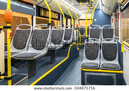 The bus inside. Grey seats and yellow handrails