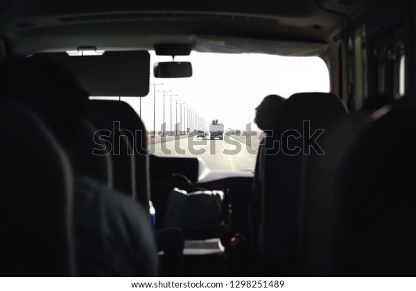Bus on highway. Coach, shuttle or minivan.\
Airport transfer with taxi van. Passenger interior view from back\
seat. Tourist tour excursion. Public transport. Inside car.\
Motorway traffic.