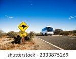 Bus on two lane asphalt road in rural Australia with kangaroo crossing sign.