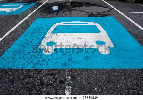 Bus parking lane sign painted in blue and white on\
cracked asphalt road. 