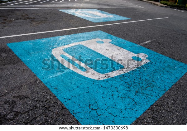 Bus parking lane sign painted in\
blue and white on cracked asphalt road. Tilted\
position.