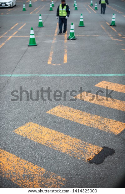 Bus parking lot in an outlet shopping arcade, green\
traffic cones with yellow traffic lines as guided with staffs to\
control the flow.
