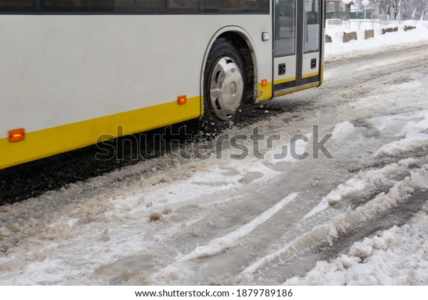 The bus\
rides through the melting snow on the\
road.