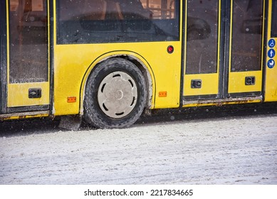 Bus Riding On Snow Covered Road, Snowfall On City Road. Public Yellow Bus Wheel In The City On Snowy Uncleaned Road, Winter Driving. Snow And Ice On Winter Roads, Dangerous Driving In Winter Season