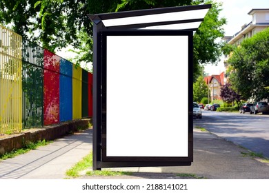 bus shelter at busstop. transit station. blank light billboard ad sign and lightbox. green urban street setting. soft background. safety glass design. white poster ad commercial poster space display.