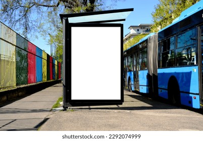 bus shelter at bus stop. white poster and commercial ad space display lightbox. base for mockup. outdoors image. blank ad panel. glass design. urban street setting. green background with spring trees