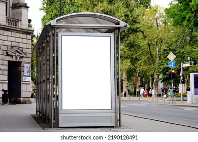 Bus Shelter At Tram And Bus Stop. Image Collage. White Poster Ad Display. Advertising Concept. Glass And Steel Design. Blurred City Park In Urban Setting With Green Trees In The Background.