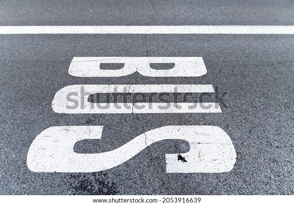 Bus sign painted on the pavement of a street\
lane, you can see the texture of the asphalt with a cracked line.\
Signal and urban concept