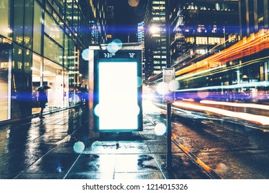 Bus Station Billboard In Rainy Night With Blank Copy Space Screen For Advertising Or Promotional Content, Empty Mock Up Lightbox For Information, Clear Display In Urban City Street With Long Exposure