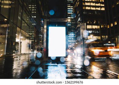 Bus Station Billboard In Rainy Night With Blank Copy Space Screen For Advertising Or Promotional Content, Empty Mock Up Lightbox For Information, Blank Display In Urban City Street With Long Exposure