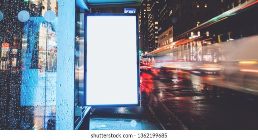 Bus Station Billboard In Rainy Night With Blank Copy Space Screen For Advertising Or Promotional Content, Empty Mock Up Lightbox For Information, Blank Display In Urban City Street With Long Exposure