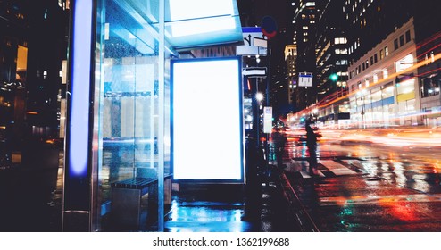 Bus Station Billboard In Rainy Night With Blank Copy Space Screen For Advertising Or Promotional Content, Empty Mock Up Lightbox For Information, Blank Display In Urban City Street With Long Exposure