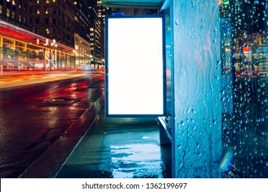 Bus Station Billboard In Rainy Night With Blank Copy Space Screen For Advertising Or Promotional Content, Empty Mock Up Lightbox For Information, Blank Display In Urban City Street With Long Exposure