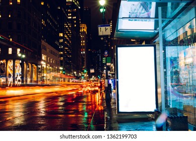 Bus Station Billboard In Rainy Night With Blank Copy Space Screen For Advertising Or Promotional Content, Empty Mock Up Lightbox For Information, Blank Display In Urban City Street With Long Exposure