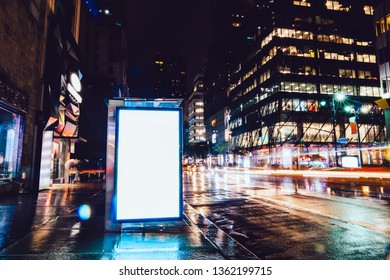 Bus Station Billboard In Rainy Night With Blank Copy Space Screen For Advertising Or Promotional Content, Empty Mock Up Lightbox For Information, Blank Display In Urban City Street With Long Exposure