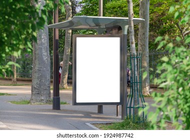 Bus Stop Billboard Mockup In Empty Street In Paris. Parisian Style Hoarding Advertisement Close To A Park In Beautiful City