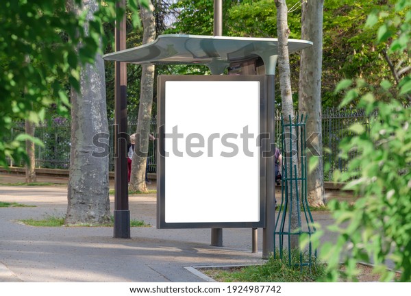 Bus stop billboard Mockup in empty street in Paris.\
Parisian style hoarding advertisement close to a park in beautiful\
city