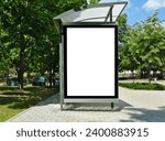 bus stop with blank white poster ad lightbox. bus shelter advertising concept. glass and aluminum. commercial poster space and display panel. green urban street. lush foliage. soft background