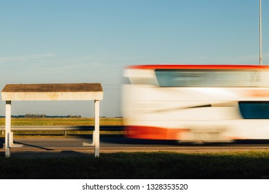 Bus stop booth while a bus passes quickly on a road