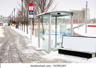 Bus Stop With A Glass Shelter Along A Street On A Snowy Winter Day. Calgary, AB, Canada.