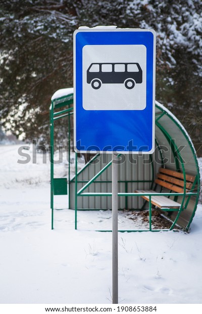 Bus stop in the middle of a\
beautiful winter road in the middle of the forest with a bus stop\
sign