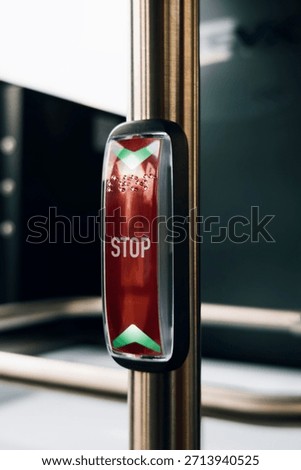 Bus stop request button with indicator lighting and raised tactile markings for accessibility.