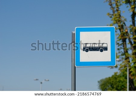 Bus stop sign on a metal pole with a sky in the background