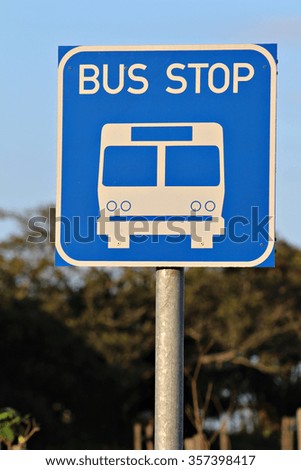 Bus stop sign on post pole next to the road. Traffic road sign. Blue signage signpost. 