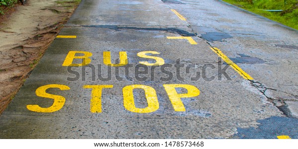 Bus stop sign painted\
on asphalt road