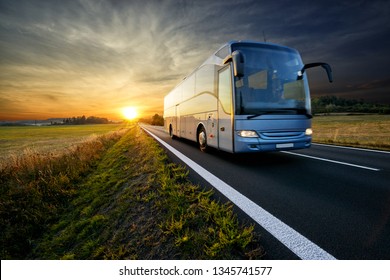 Autobús viajando por la carretera de asfalto en el paisaje rural al atardecer