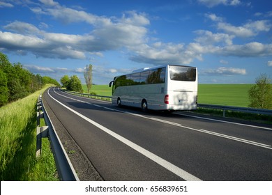 Bus traveling on the asphalt road along the green fields and alleys in the countryside