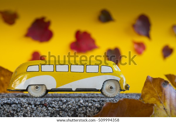 Bus trip in the fall. Antique toy car in\
autumn landscape.