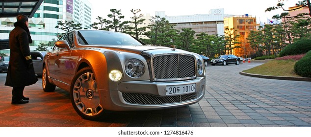 Busan, South Korea - December 3, 2011: A Valet Waits By A Bentley Luxury Sedan Car. Taken In Front Of A Casino In Busan, South Korea, But Suitable To Illustrate Wealth, Luxury, And Wealthy Lifestyle.