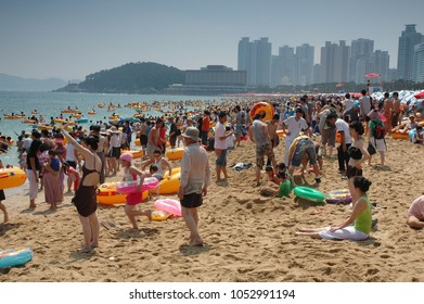 Busan, South Korea, Summer: A Very Large Big Crowd Of People On The Beach During The Summer By The Ocean. Skyscrapers In The Background.