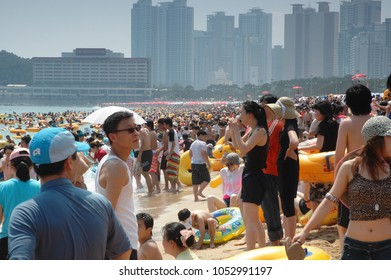 Busan, South Korea, Summer: A Very Large Crowd Of People On The Beach During The Summer By The Ocean. Skyscrapers In The Background.