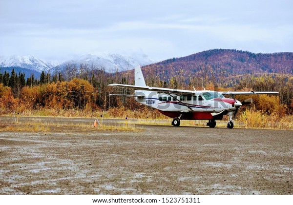 Bush plane in Kaltag, Alaska arrives\
after flying over foggy mountains during fall\
time