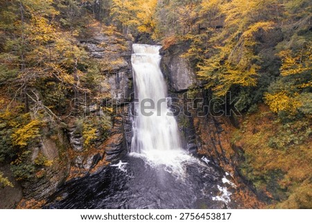 Bushkill Falls waterfall flowing through rocky cliffs with colorful autumn foliage in the Pocono Mountains, Pennsylvania.