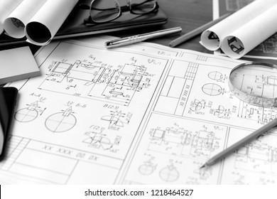 Business accessories (laptop, smartphone, pens, magnifier), accessories for drawing (plans, rulers) and learning on the table