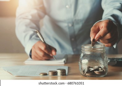 business accounting with saving money with hand putting coins in jug glass concept financial